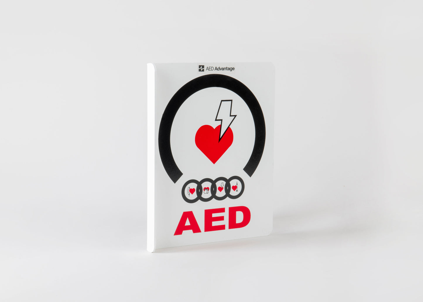 A white plastic rectangular wall sign containing large bold text indicating an AED is present