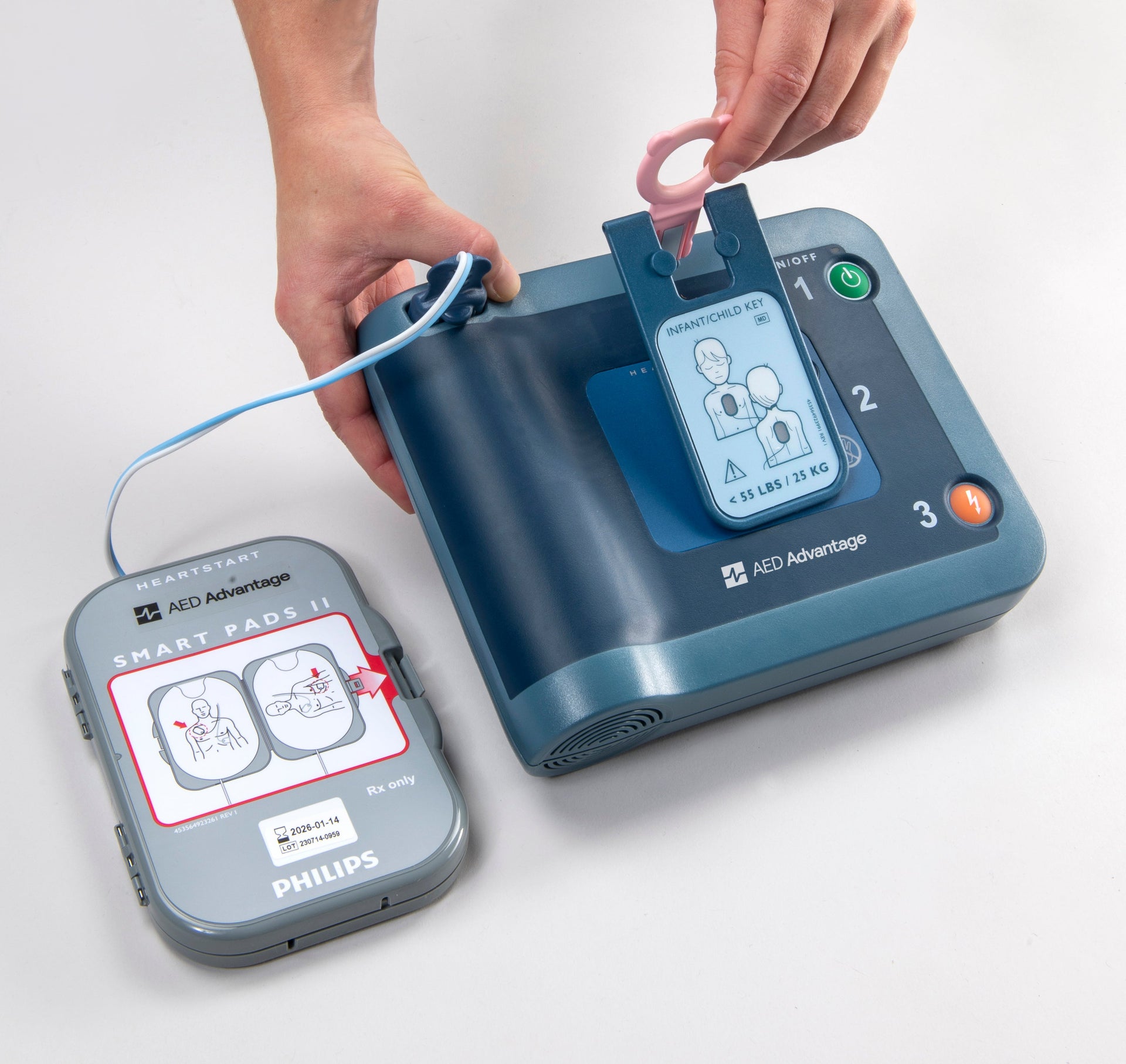 Someone is inserting a pediatric key into a blue Philips HeartStart FRx AED