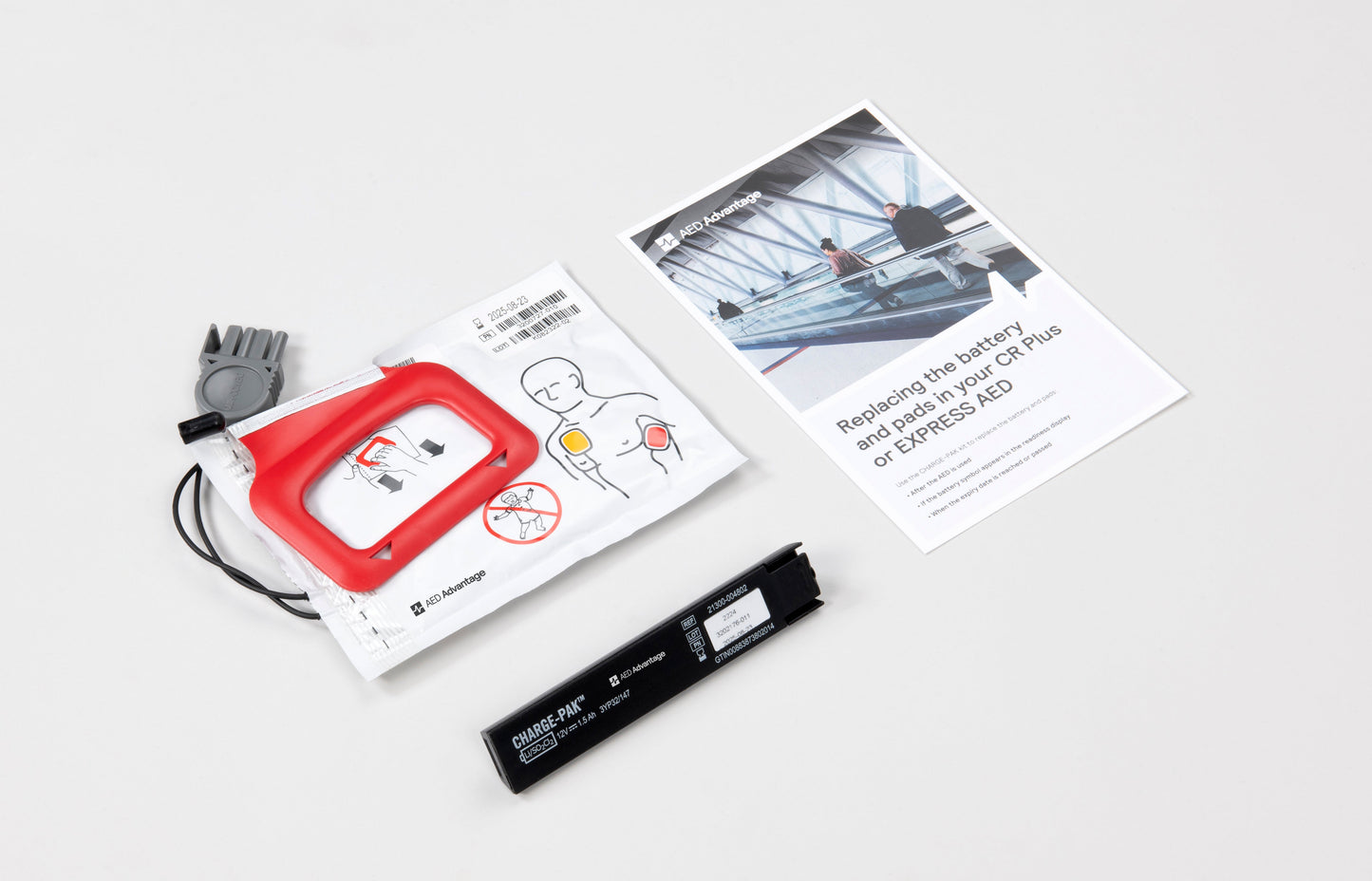 White foil package containing adult AED pads, a small black battery, and an instruction booklet 