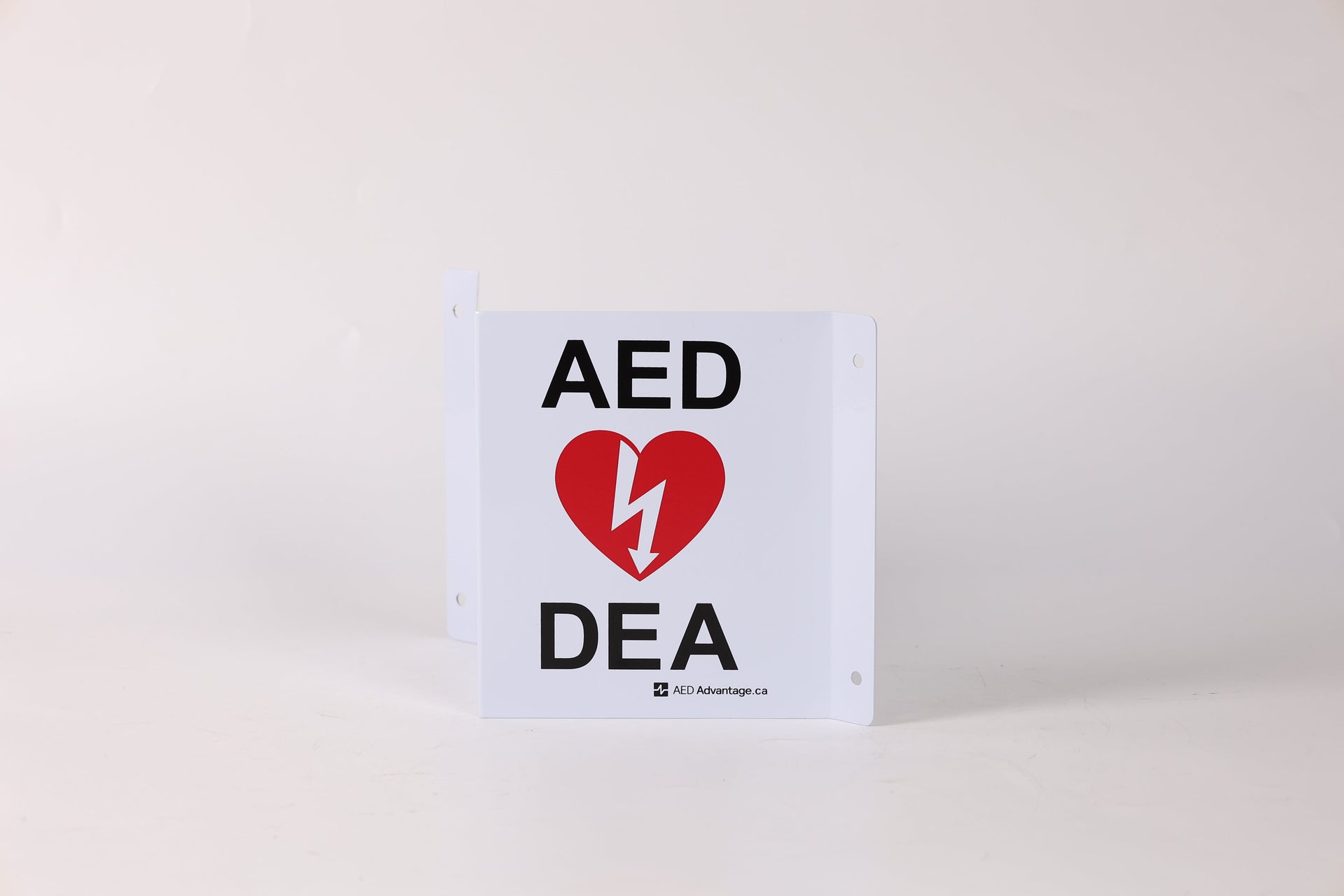 A tent-shaped 3D metal wall sign that marks an AED is present to individuals approaching from any direction