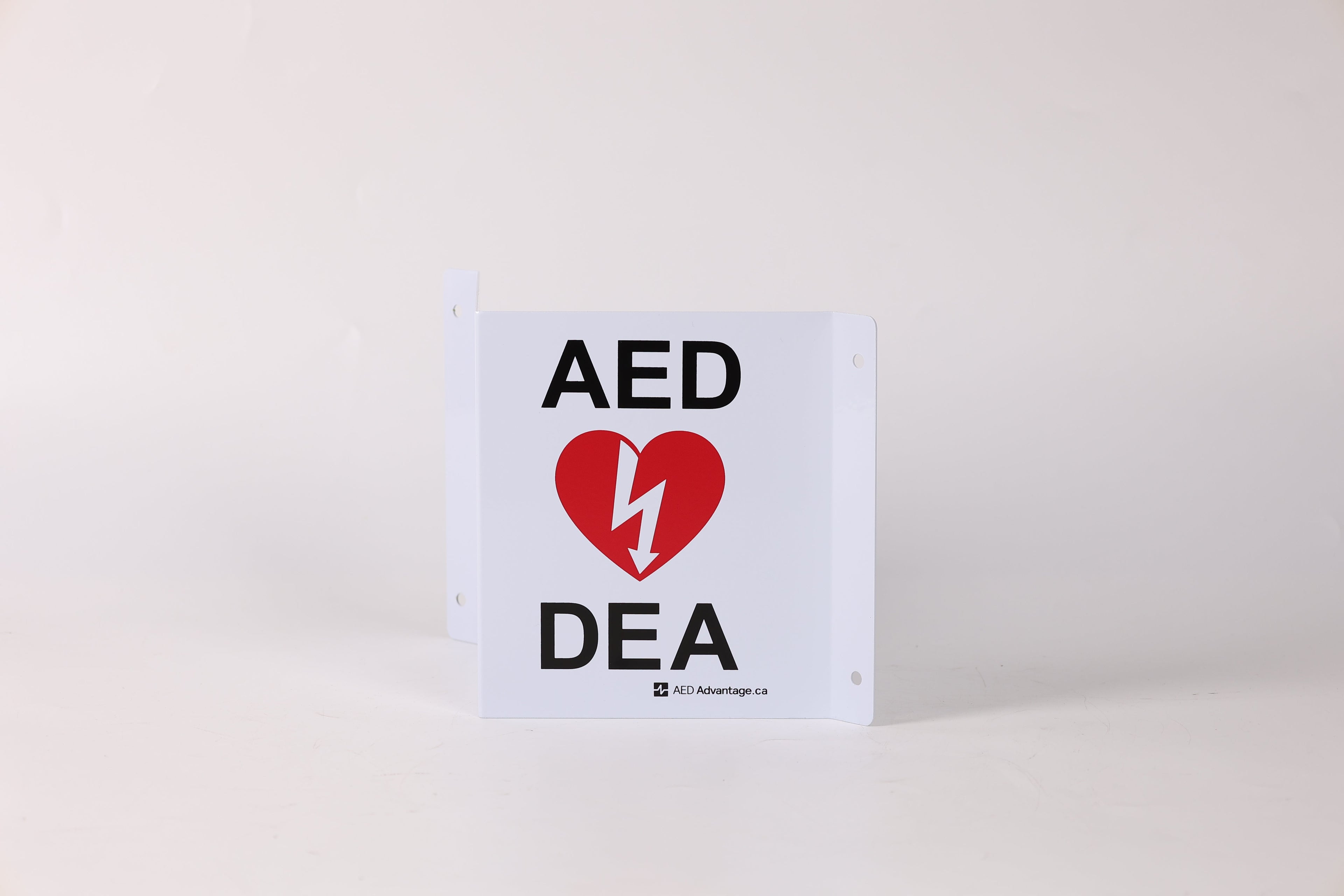 A tent-shaped 3D metal wall sign that marks an AED is present to individuals approaching from any direction