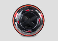 A black and yellow, spherical defibrillator cabinet with red arrows indicating which way to turn the lid to open it