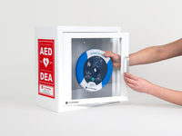 A blue and white HeartSine 360P AED being retrieved by hand from a white metal cabinet with red decals