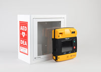 A black and yellow LIFEPAK 1000 AED standing in front of a white metal cabinet with red decals