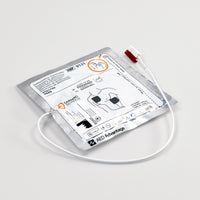 A white and silver square foil package with a white connector cord containing electrodes for the Powerheart G3 defibrillator