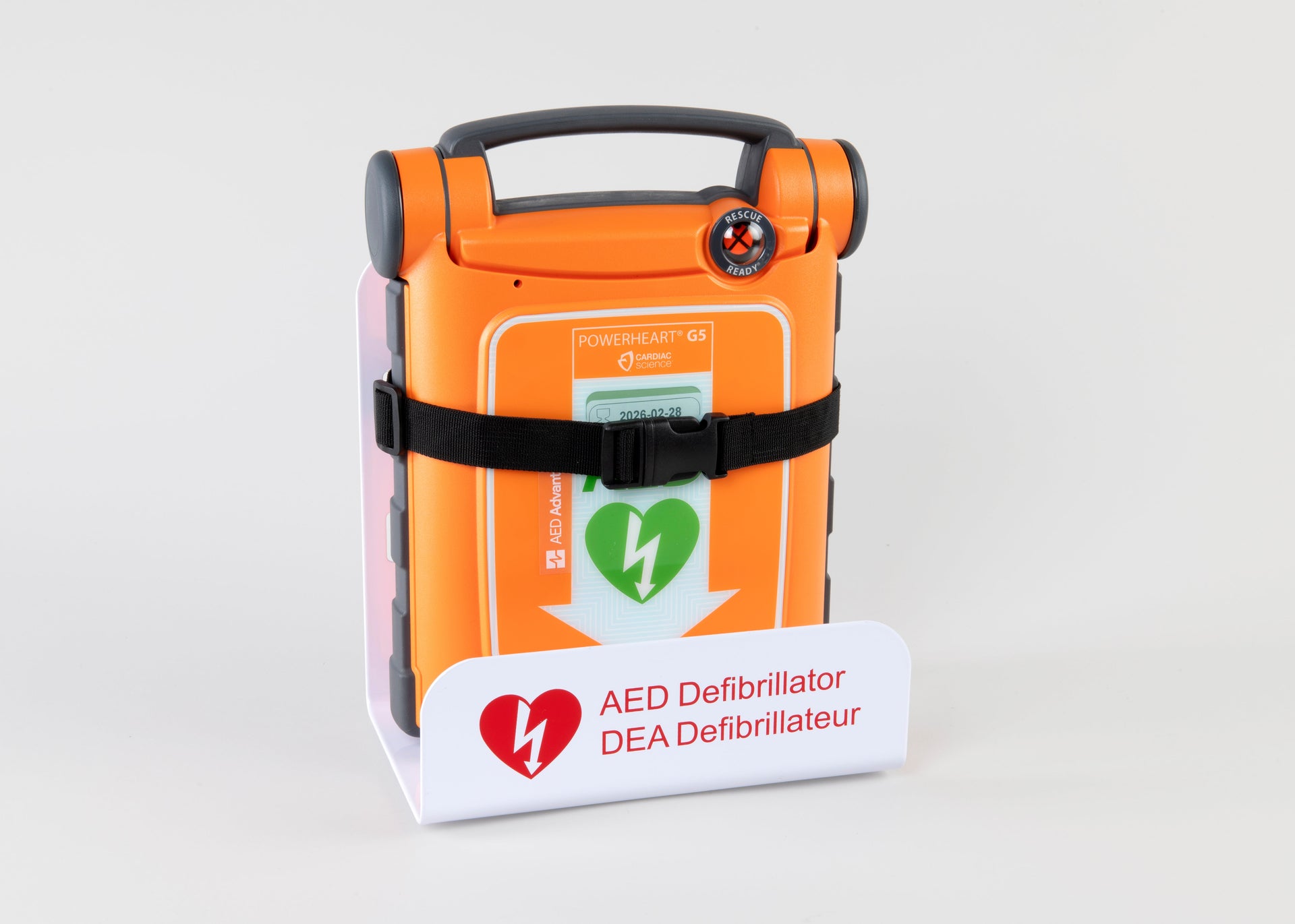 An orange Powerheart G5 AED strapped into a white metal wall mount bracket