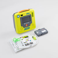 A green ZOLL AED 3 machine standing next to its green semi-rigid carry case